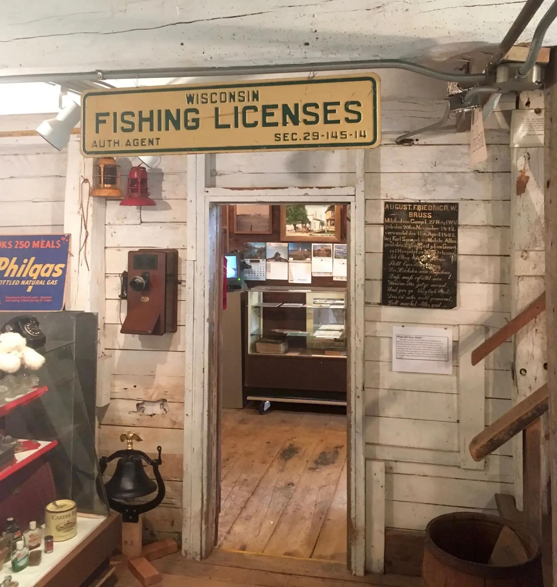 A vintage Wisconsin Fishing Licenses sign over a doorway in the general store, an antique wall telephone alongside