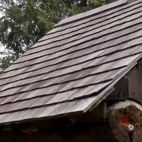 Courses of weathered hand-split cedar shingles on the roof of the historic Smokehouse
