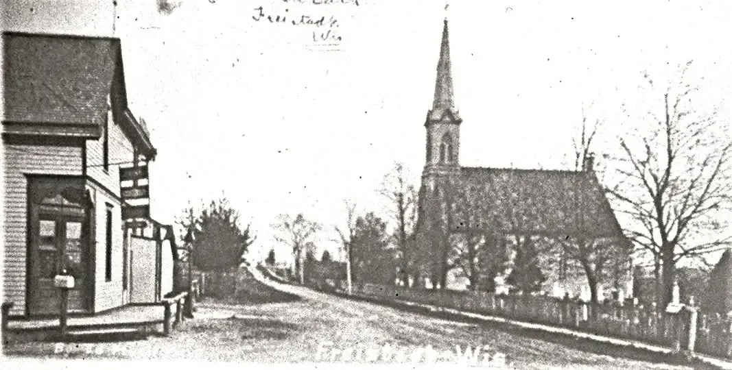 Historic photograph of the dirt road through Freistadt with the steepled 1884 Trinity church on the right