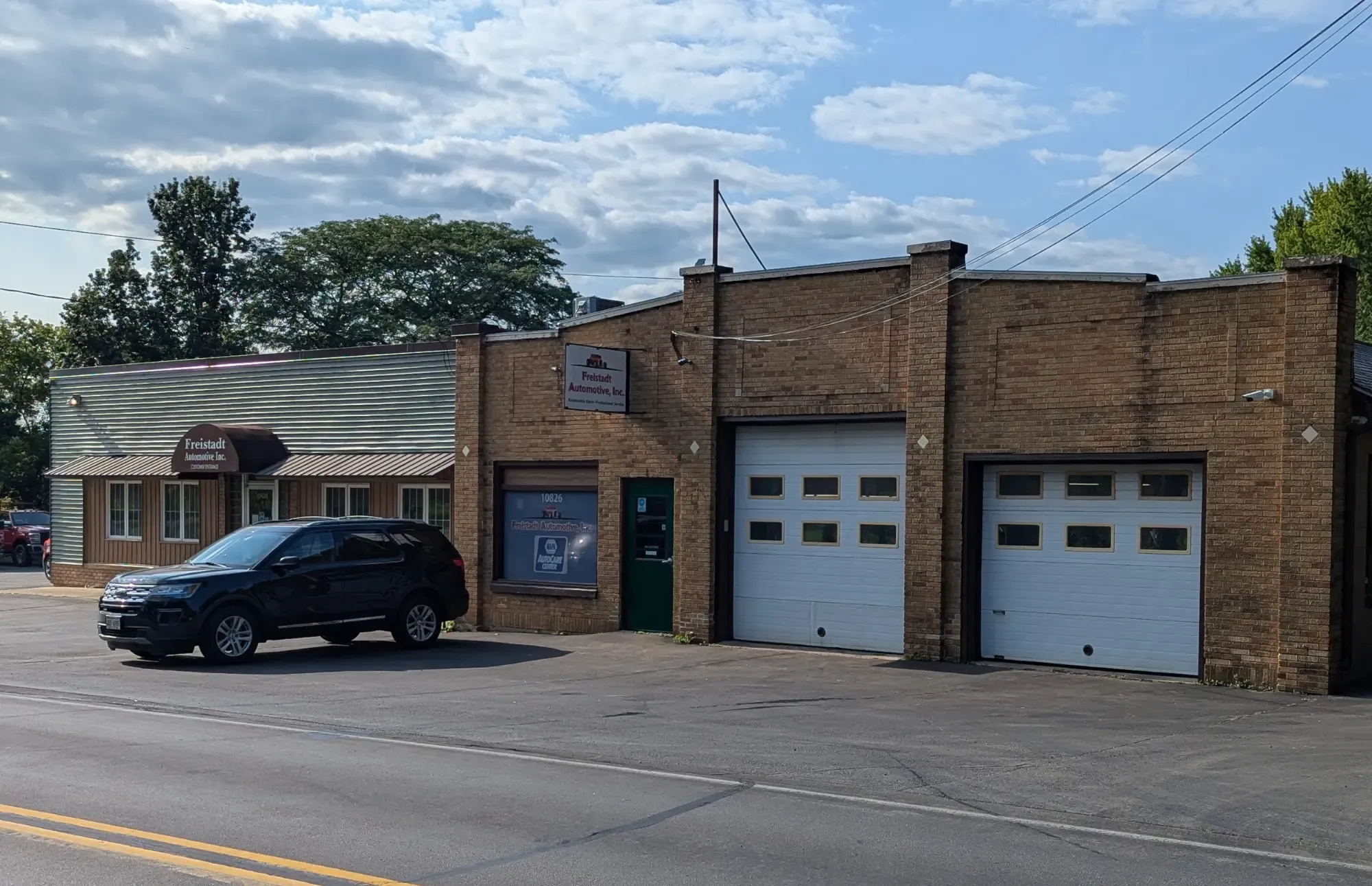 The brick Freistadt Automotive garage on Freistadt Road, its two white service doors closed and a car parked out front